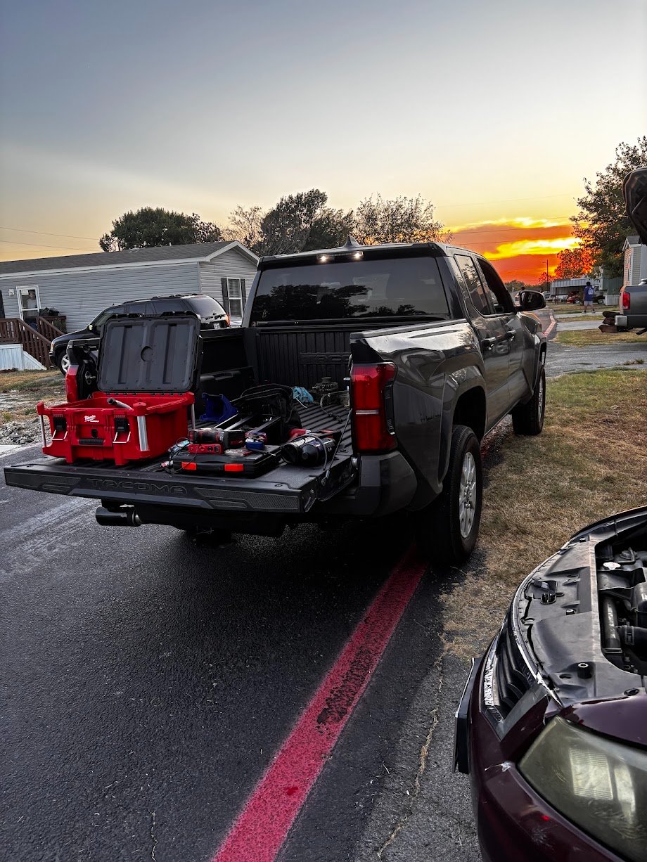AR Brothers service truck bed packed with tool cases, parked curbside at sunset on a repair call